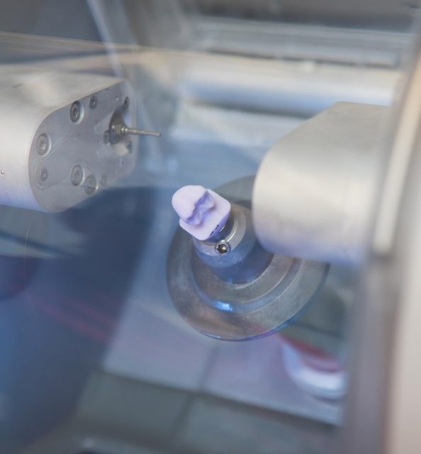 In-office milling unit carving ceramic crown for CEREC same-day dental restoration.